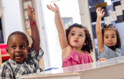 Three children raising hands in class